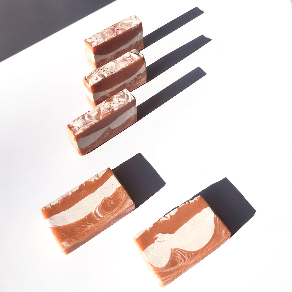 orange and white soap bars on a table with harsh shadow