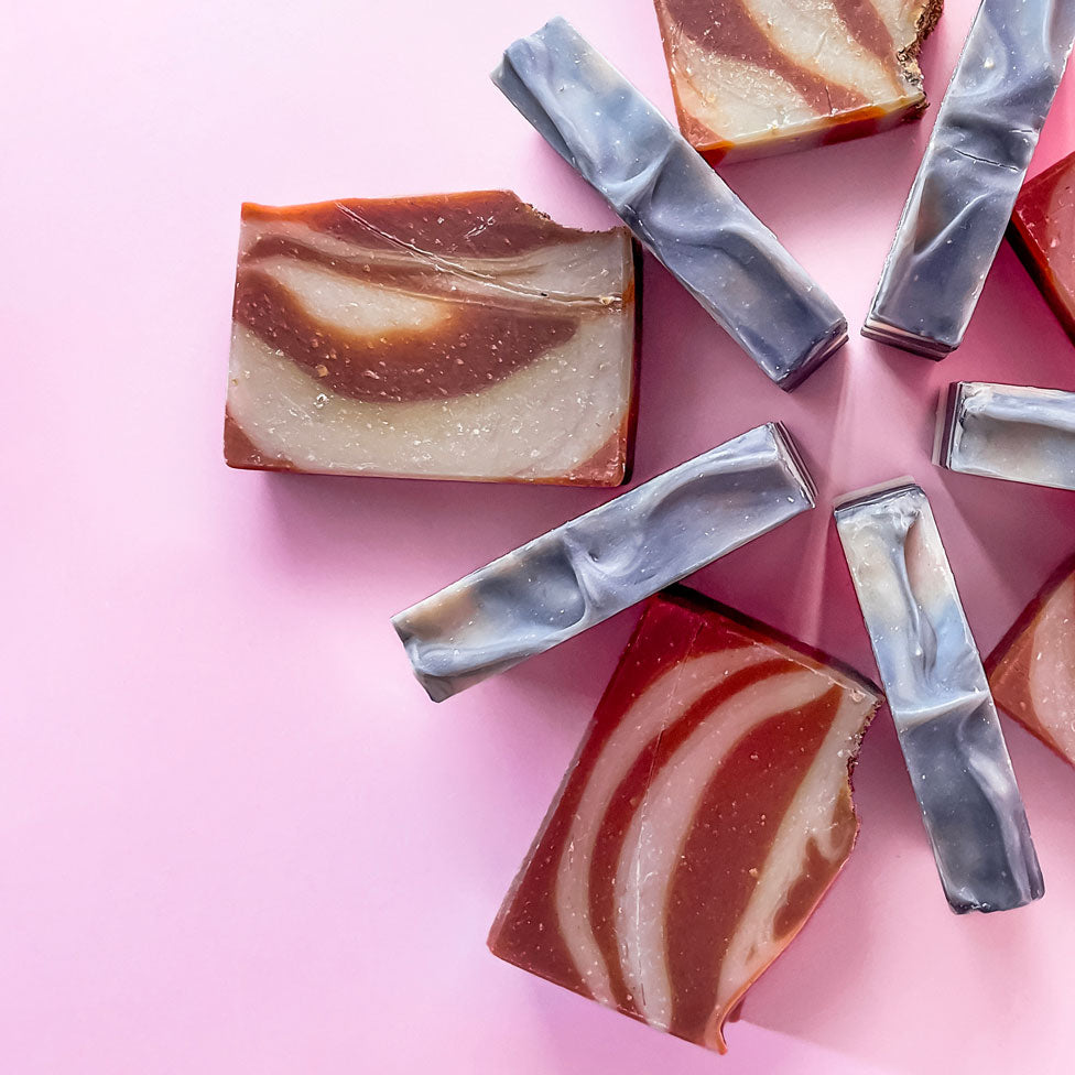 brown and grey soap bars in semi circle on pink background