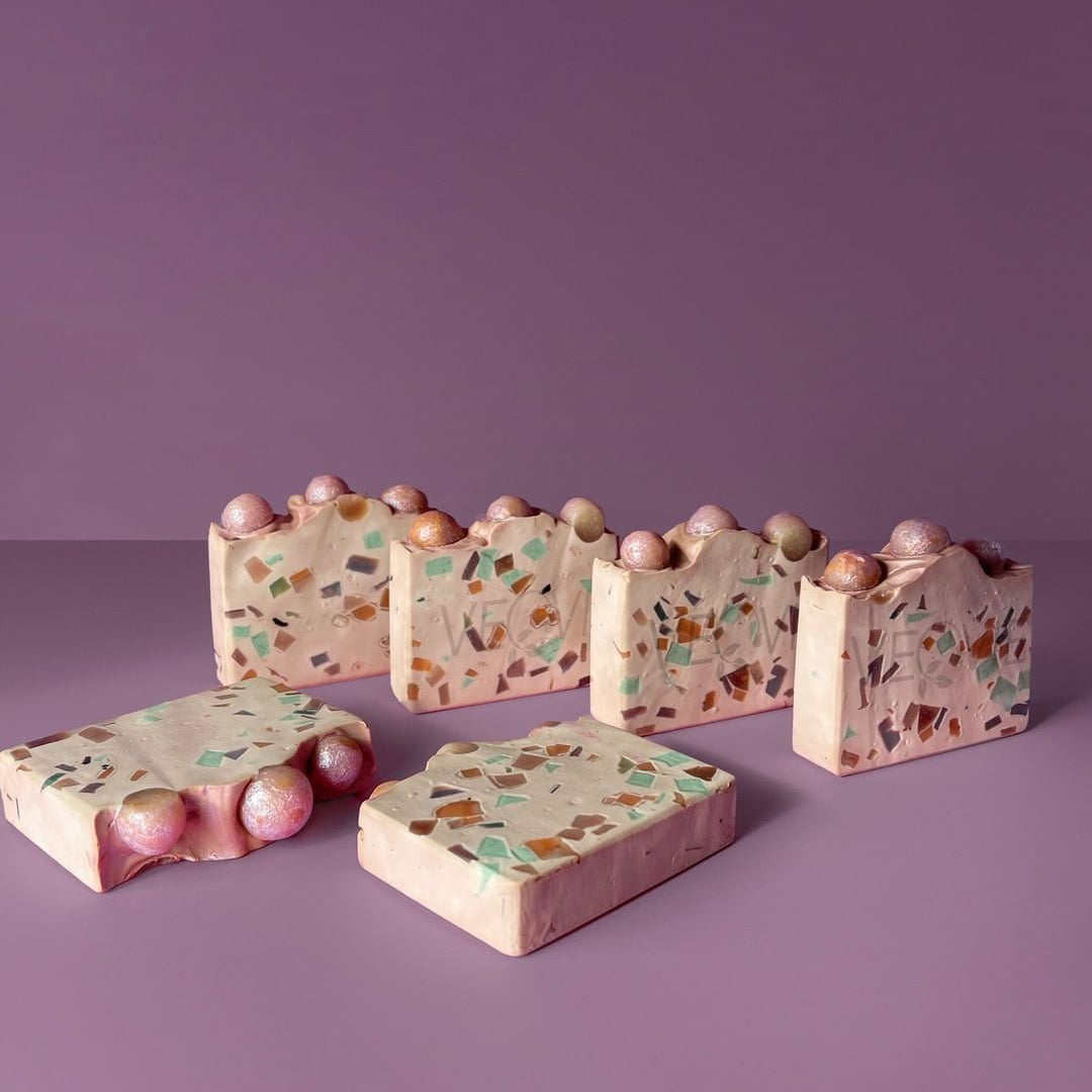 confetti soap bars with pink balls on top on a purple background