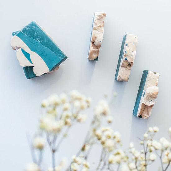 blue and white soap bars on a table with blurry flowers on the corner