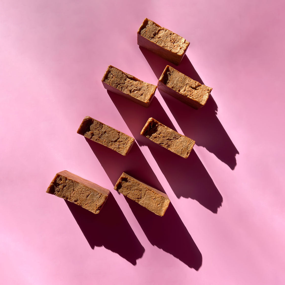 rustic golden brown soap bars on a pink background